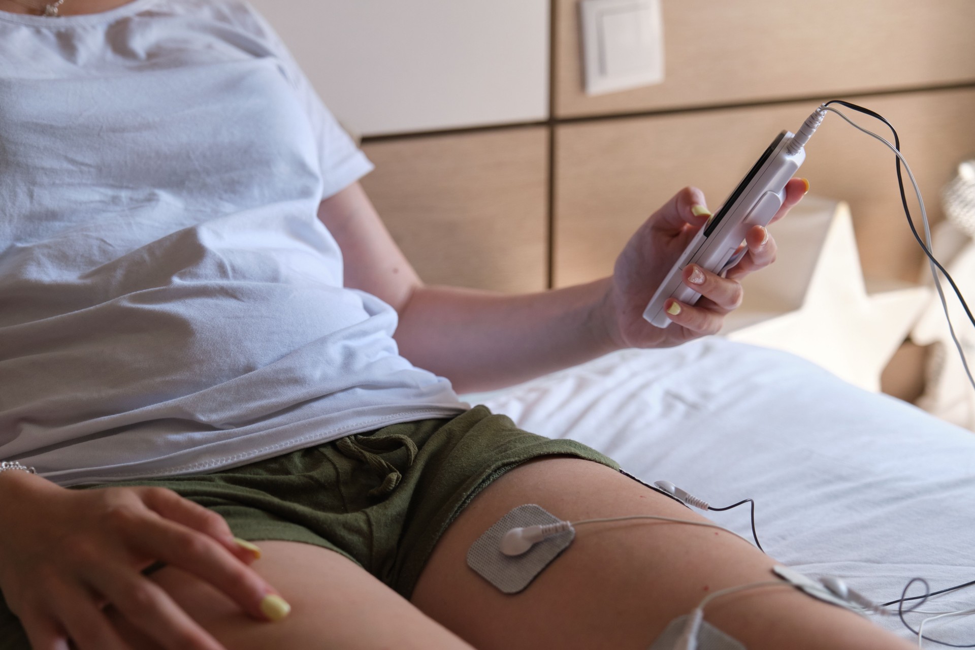 electrostimulation treatment at home, electrodes on the leg of an unrecognizable woman, getting a treatment of tens, ems or massages to improve muscle health and improve blood circulation. injury recovery